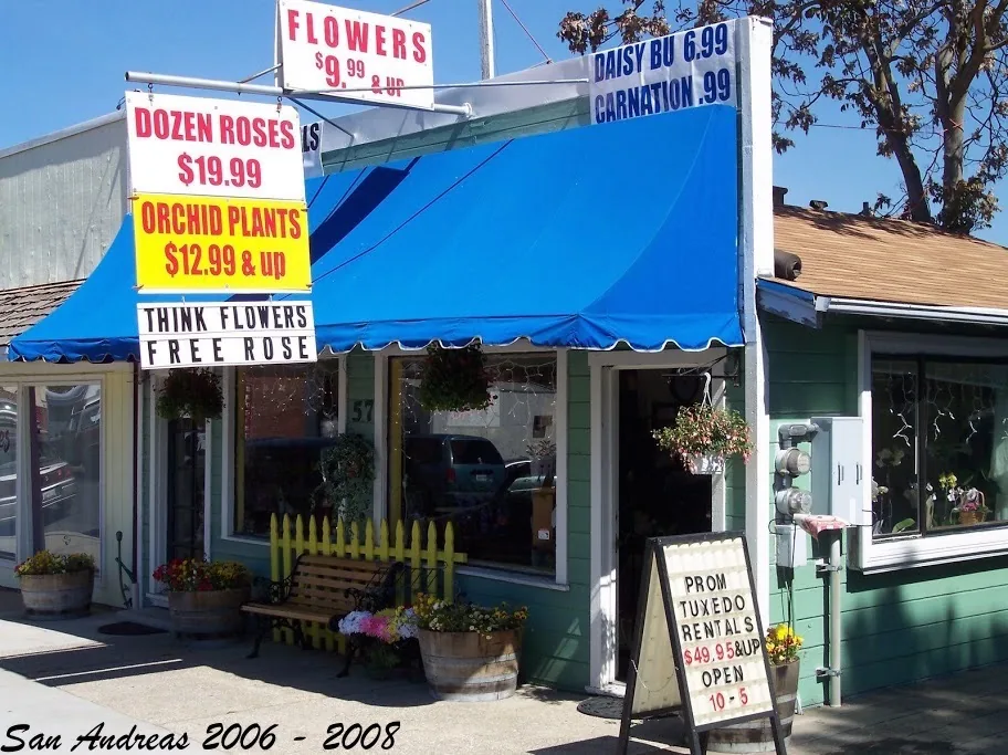 The green-and-blue San Andreas storefront with rose and orchid price signs and a prom tuxedo rentals sandwich board