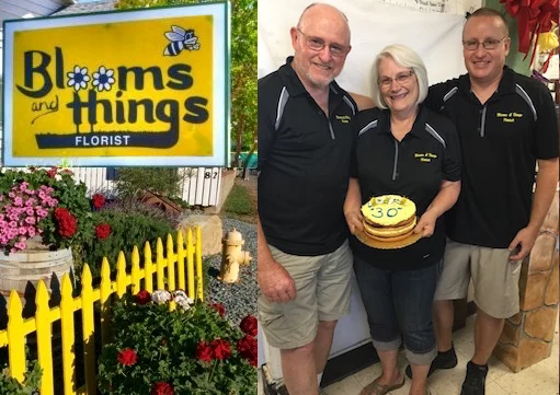 The yellow Blooms & Things sign behind a picket fence, beside a photo of Ron, Vicki and Mark McFall holding the 30th-anniversary cake