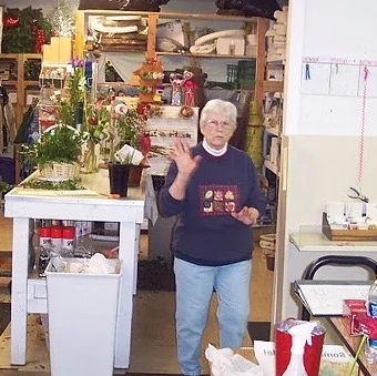 A wave from the workroom of the Arnold shop, shelves stacked with ribbon and supplies
